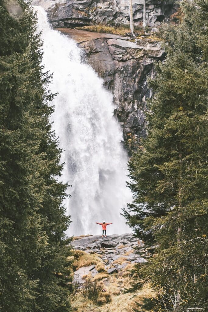 person in front of waterfall with open arms