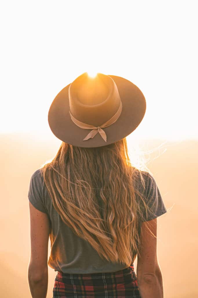 woman with hat looking into the sun